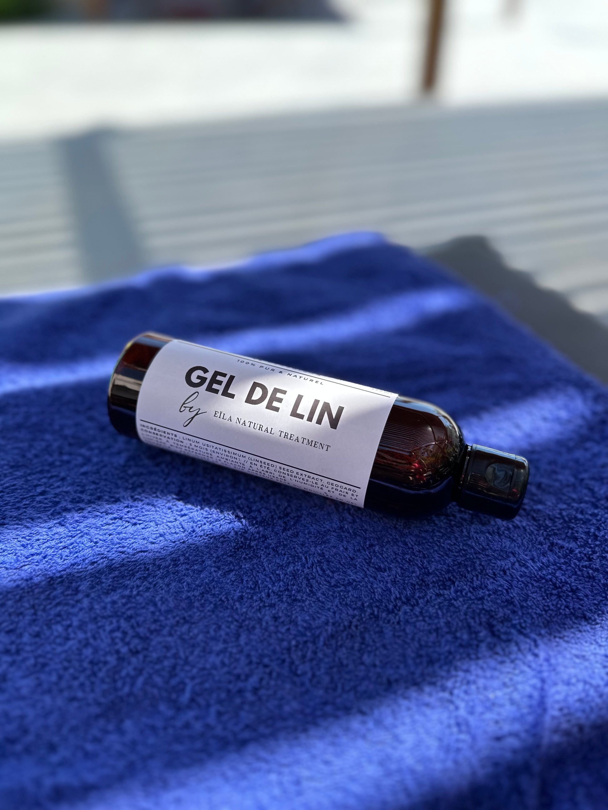 Flacon de Gel de Lin Pur Eïla posé sur une serviette en extérieur